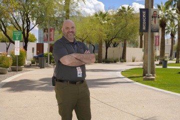 Man wearing a grey t-shirt and dark khaki pants stands in the Phoenix Bioscience Core campus.