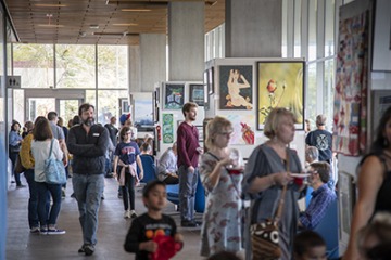 Attendees look at art during the 10th annual "On Our Own Time" art exhibit featuring art made by University of Arizona employees and their immediate family members.
