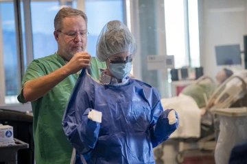 Health care workers don personal protective equipment, known as PPE, before treating patients with the virus that causes COVID-19. Some research conducted during the pandemic included efficacy of PPE to protect against the virus’ spread.