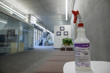 Spray bottle of disinfectant sitting on a table with the office of the Health Sciences Innovation Building in the background. 
