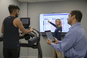 The Sensor Lab features several rooms that can be configured in a variety of ways to suit the needs of each research project. Here, Drs. Barton and Almeida collect data from a study participant as he uses a treadmill. 