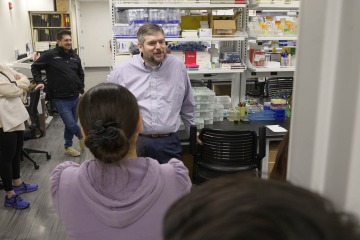 Male researcher speaks with students in his lab. 