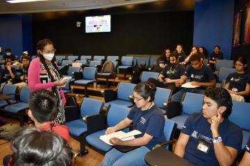 Female university professor wearing a mask teaching nursing students in a lecture hall.