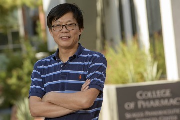 portrait of wei wang in front of College of Pharmacy sign