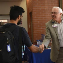 Dr. Moreno shaking hands with a male student.