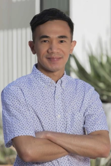 Portrait of a young professor with arms crossed and smiling while standing outside. 