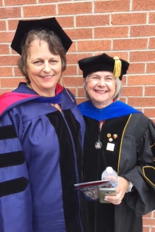 Photo of Lorre Laws dressed in a mortar board and robe alongside dissertation chair Lois Loescher.