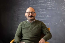 Portrait of University of Arizona Cancer Center researcher Ghassan Mouneimne, PhD, sitting in front of a chalk board