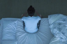 Person sitting at edge of the bed unable to sleep