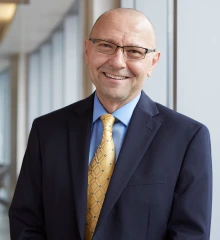 Portrait of Dan Theodorescu, MD, PhD, wearing a dark jacket and tie and smiling.