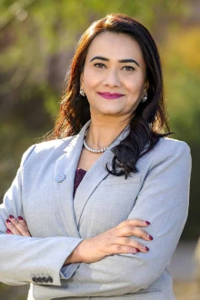 Portrait of Dr. Hina Arif standing outside wearing a light gray blazer and smiling.