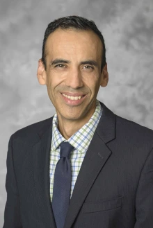Portrait of Gustavo Perez, PhD, wearing a suit coat and tie with a plaid shirt