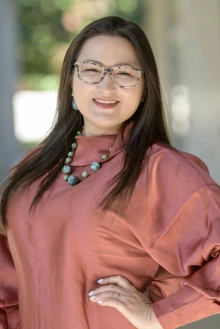 Portrait of Amanda Wilson standing in an outside corridor smiling.