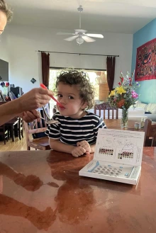 A boy sitting at a table taking medication by spoon