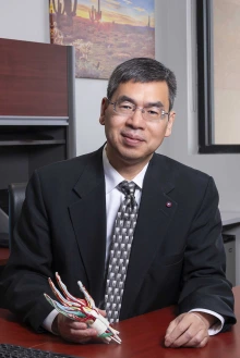 Portrait of Zong-Ming Li, PhD, in a suit and tie, seated at a desk.