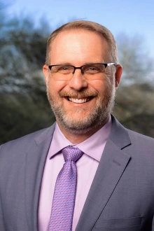 Portrait of middle-aged white man in a suit and tie smiling. 