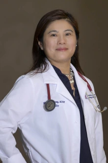 Portrait of a middle-aged Asian woman in medical white coat smiling.