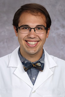 Portrait of a smiling young male doctor wearing a white coat and a bow tie. 
