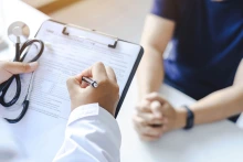  Doctor giving prescription to a patient and filling out medical form on a clipboard