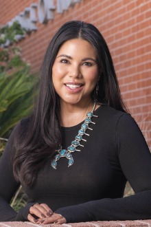 Portrait of a young Native American woman with long dark hair smiling.