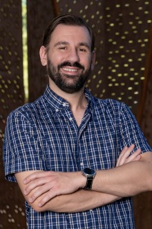 Portrait of young man with beard smiling with arms crossed in short sleeved button-up shirt