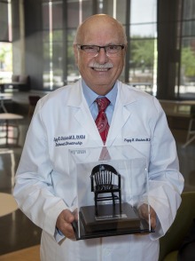 Fayez K. Ghishan, MD, holds the symbolic chair representing the endowed directorship, and wears his new white coat embroidered with “endowed director” as his new title.