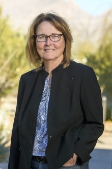 Portrait of Ann Cress, a white woman with shoulder-length light brown hair, wearing a dark blazer and glasses.