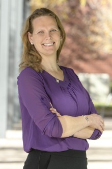 Portrait of Kacey Ernst, a white woman with light brown hair, wearing a purple blouse and smiling. 