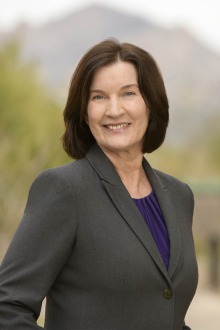 Portrait of Terry Badger, a white woman with shoulder-length dark hair, wearing a blazer and black blouse