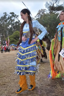 Native American woman wearing traditional tribal attire doing a jingle dance.