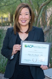 Dr. Joyce Lee-Iannotti standing outside smiling holding a certificate. She is an Asian woman with medium length strait brown hair with highlights. 