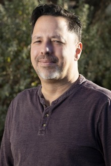 Portrait of Kevin Phillips standing outside wearing purple shirt.
