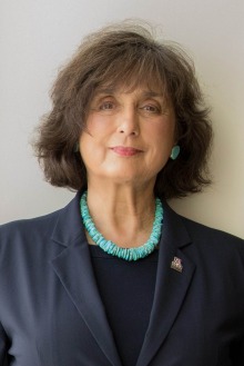 Portrait of Roberta Brinton wearing a dark blazer and blouse with a turquoise necklace. 