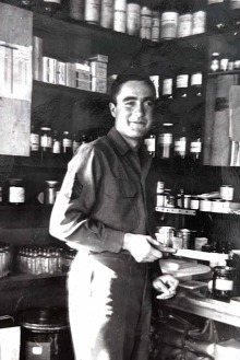 Alt Text: Albert Picchioni stands in front of shelves full of medications in a black and white photo marked 1944.