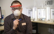 Tory Middlebrooks, of University Libraries, models a face shield, which is designed to be worn in conjunction with addition PPE such as a mask. Middlebrooks mans the 3D printers that produced the headbands for the face shield. (Photo: Kris Hanning, University of Arizona Health Sciences)