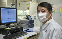 Yin Chen, PhD, associate professor at the UArizona College of Pharmacy, analyzes a gel image of interferon responsive proteins. (Photo: Kris Hanning/University of Arizona Health Sciences)