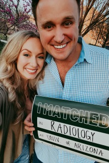 A man and woman pose together while he holds up a sign that says "I matched in Radiology at the University of Arizona."