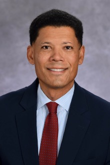 Portrait of Dr. Wayne J. Franklin wearing a black suit with a red tie