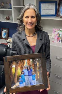 Woman (Dr. Gilbertson-Dahdal) holds a photo of her family.