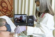 Dr. Elaine Situ-LaCasse (pictured here on the larger tablet device between the patient and physician) receives a live stream of the exam results and assists in diagnosing a mock patient during training via telehealth consultation with Julia Brown, MD (right), emergency department medical director at the Copper Queen Community Hospital in Bisbee, Arizona. (Photo: University of Arizona Health Sciences, Kris Hanning)