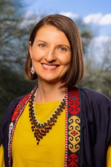 Portrait of a middle-aged white woman with brown hair smiling. 