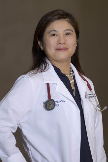 Portrait of a middle-aged Asian woman in medical white coat smiling. 